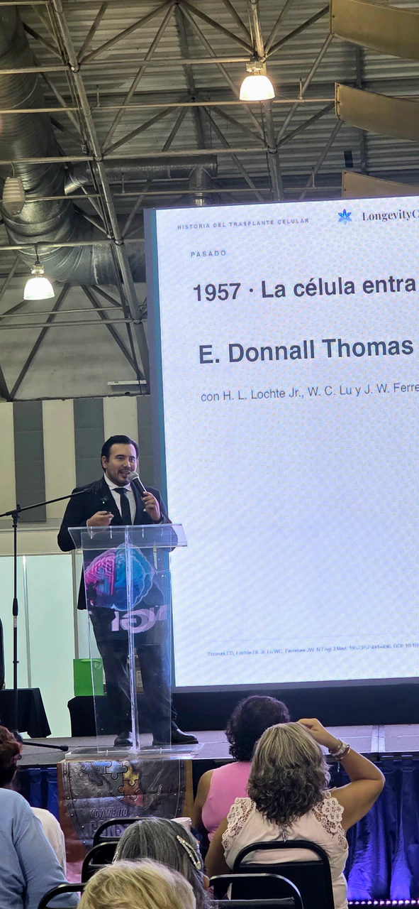 Ponente en el podio frente a una diapositiva sobre la historia de la terapia celular