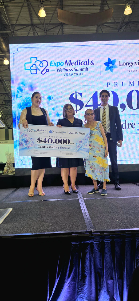Personas ganadoras con el cheque de 40,000 pesos en el escenario, junto a un integrante del equipo de Longevity Clinic