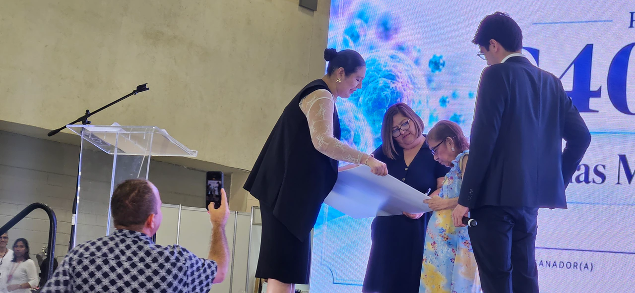 Momento en que se entrega el cheque del premio en el escenario mientras el público toma fotos